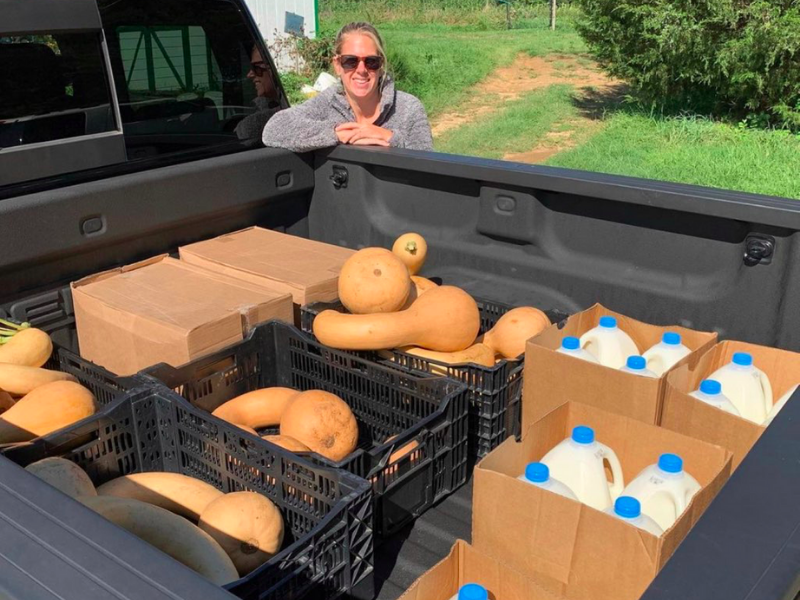 Getting ready to distribute in Alexandria, VA Woman standing outside pickup truck with squash and milk for food relief distribution